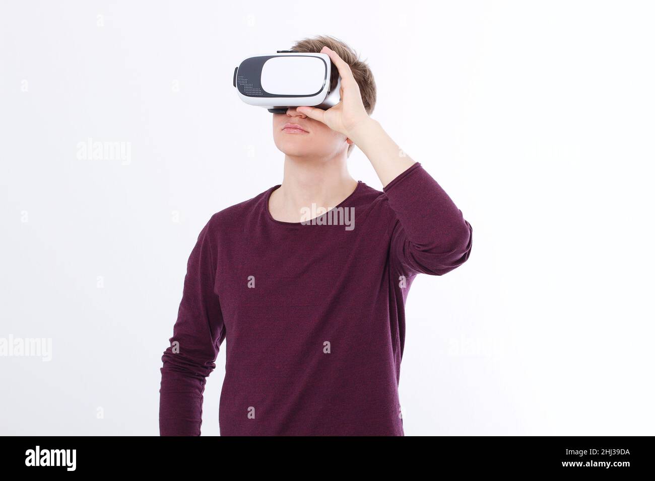 Giovane uomo che indossa occhiali per realtà virtuale isolati su sfondo bianco. Copia lo spazio e riponi. Smartphone e visore VR. Immagine orizzontale Foto Stock