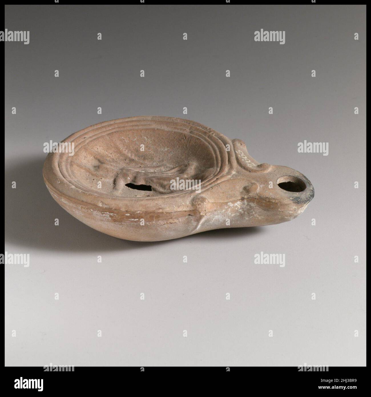 Lampada ad olio di terracotta ca. A.D. 40–100 Loeschcke romano tipo 4. Realizzato in stampo. Discus: Nike (Victory) alata in piedi sul globo, rivolta in avanti, con la corona in mano destra tesa e il palmo lungo in mano sinistra abbassata; un singolo foro di riempimento in basso a sinistra; banda di linee e scanalature sul bordo. Ugello a spirale. Anello base incisa, e piatto base.Complete, ad eccezione di un foro sul lato destro del disco proprio di Nike. Lampada ad olio di terracotta 241488 Foto Stock