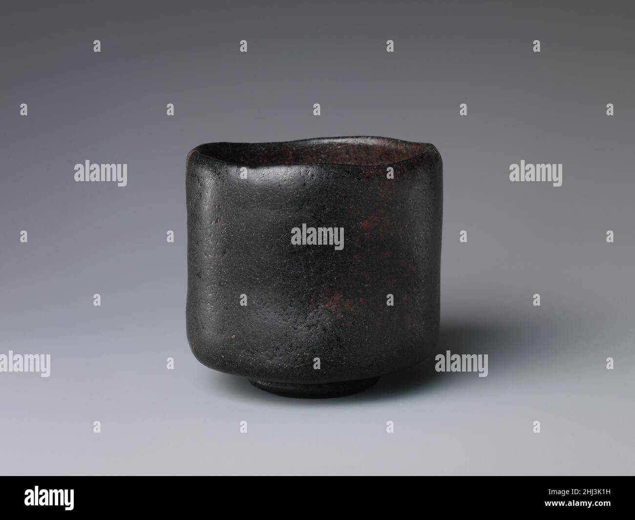 Black Raku Tea Bowl inizio 17th secolo Giappone Raku ware è un tipo di ceramica altamente stimato nella cerimonia giapponese del tè. Si tratta di una leggera terracotta vetrata stampata a mano piuttosto che gettata sulla ruota di un vasaio. L'argilla è ruvida e senza pretese, ricoperta da uno smalto opaco, come vediamo qui. Raku ware potrebbe essere cotto in piccoli forni interni, che hanno contribuito alla sua popolarità nella città di Kyoto, un importante centro di tè. È tradizionalmente associato alla famiglia di vasai Raku, che traccia il suo lignaggio indietro al tempo del famoso maestro del tè Sen no Riky?, e che ancora produce Ra Foto Stock