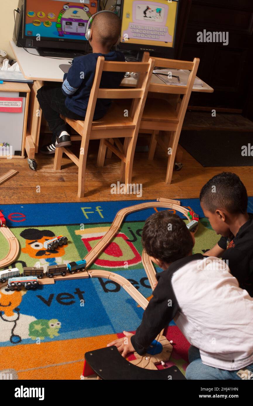 Istruzione Preschool 4-5 anni due ragazzi che giocano con il set, ragazzo in background utilizzando il desktop in background Foto Stock