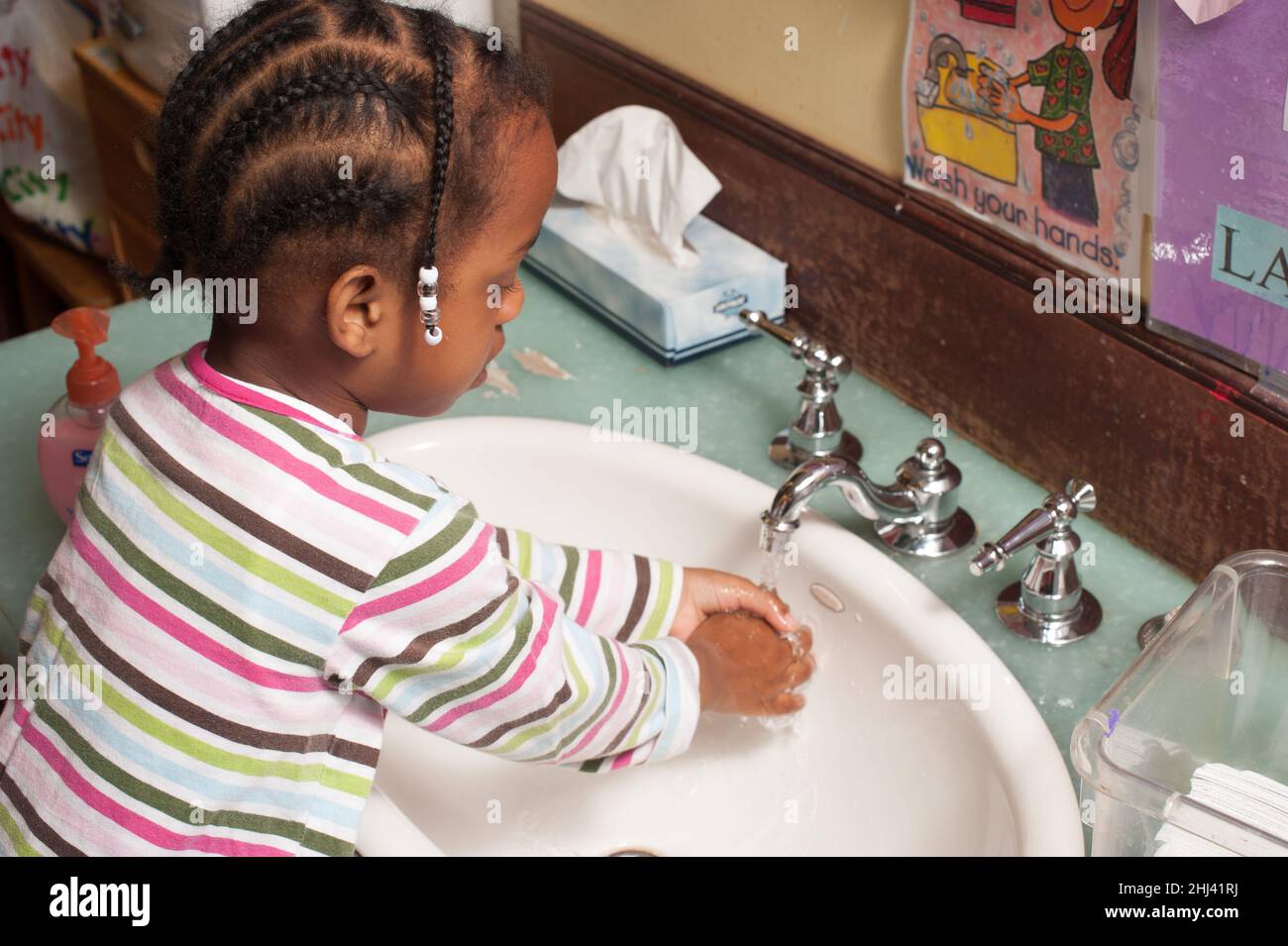 Istruzione Preschool 3-4 anni ragazza lavarsi le mani al lavandino Foto Stock
