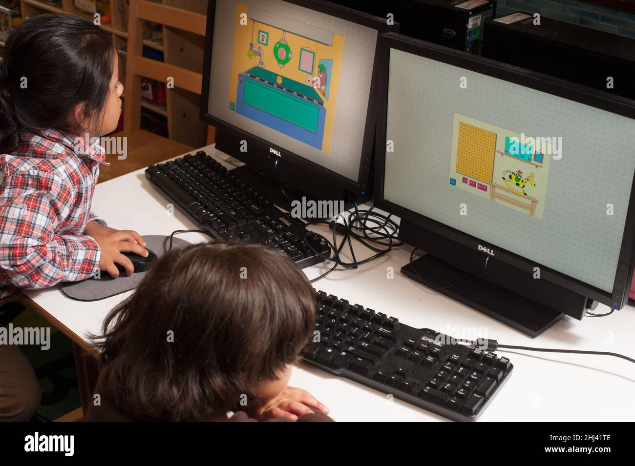 Istruzione Preschool 3-4 anni due bambini seduti fianco a fianco giocando a giochi educativi sui computer Foto Stock