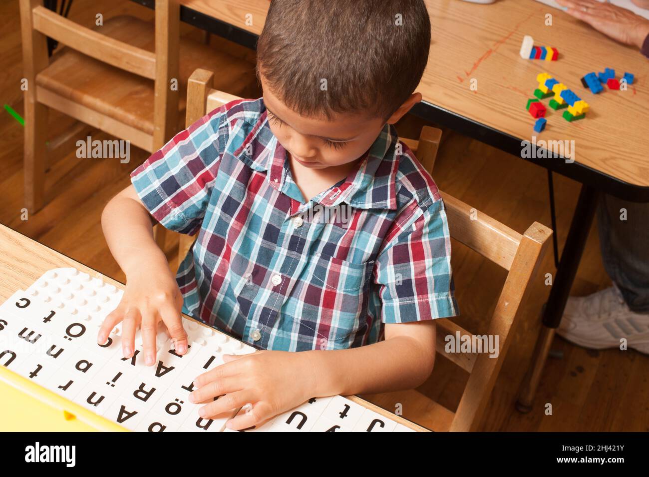 Istruzione Preschool 4-5 anni ragazzo seduto al tavolo giocando con alfabeto lettere gioco Foto Stock