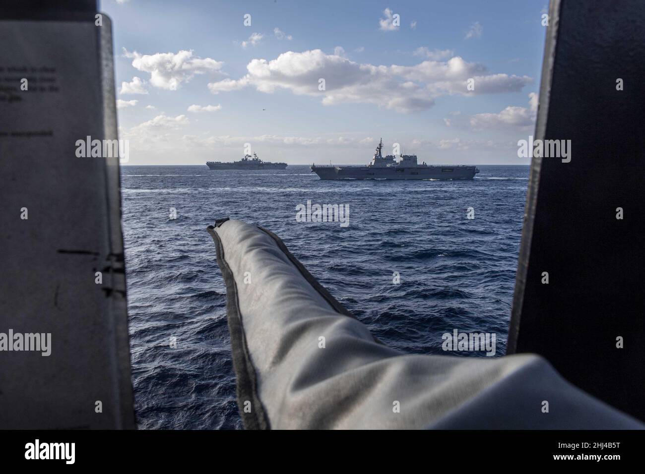 MAR DELLE FILIPPINE (Gen. 22, 2022) la nave d'assalto anfibio di classe Wasp USS Essex (LHD 2), sinistra, e la nave della forza di autodifesa marittima giapponese JS Hyuga (DDH 181) vapore in formazione con la nave d'assalto anfibio dispiegata in avanti USS America (LHA 6). Operando come parte della U.S. Pacific Fleet, Essex e America, insieme a JS Hyuga, stanno conducendo corsi di formazione per preservare e proteggere una regione indopacifica libera e aperta. (Foto di Specialista di comunicazione di massa 3rd classe Theodore Lee) Foto Stock