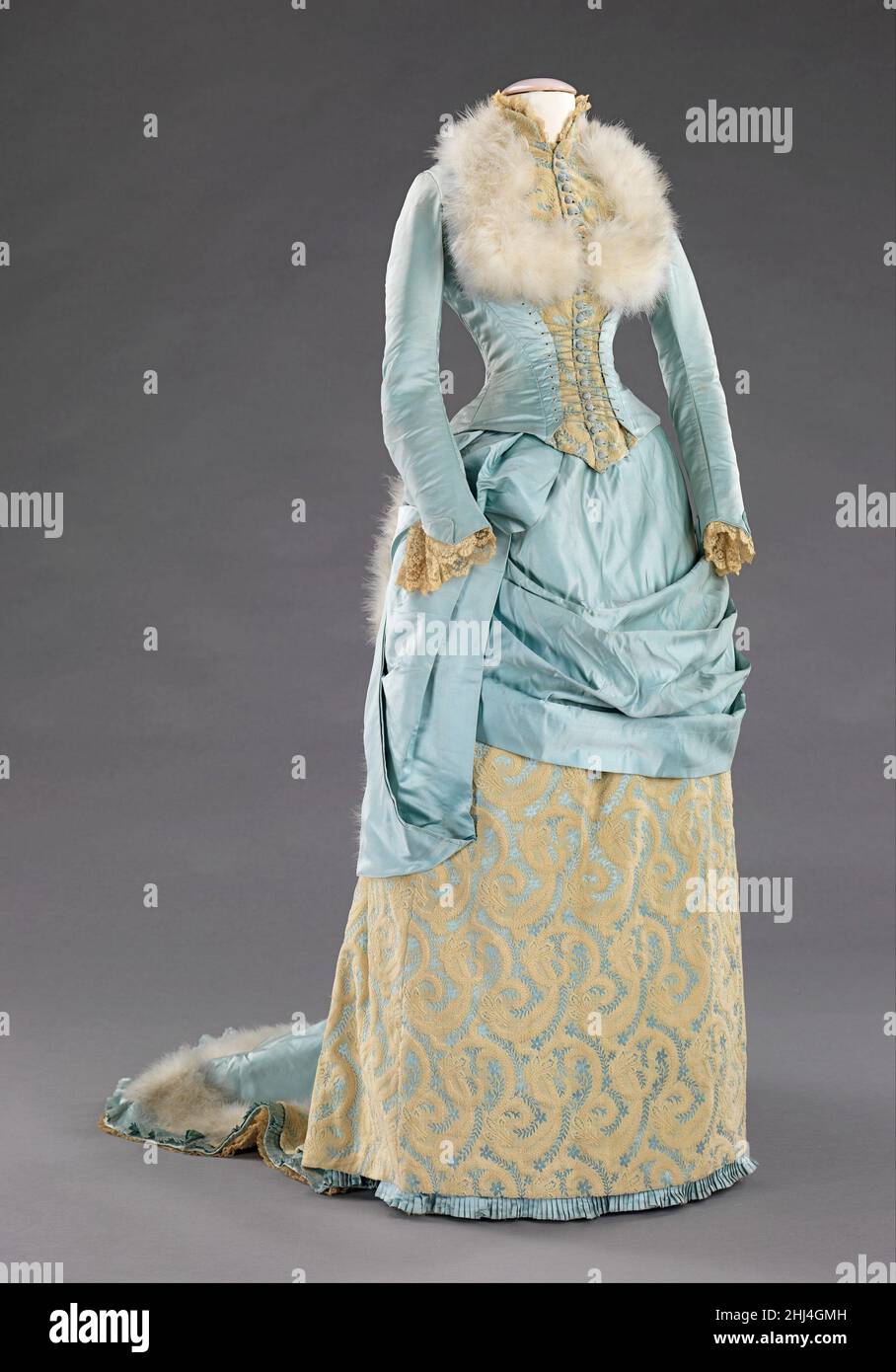 Abito da sera 1885 R. H. White & Co. American la silhouette trambusto, Anche se principalmente associato con la seconda metà del 19th secolo, originò in moda precedente come un semplice urto alla parte posteriore del vestito, come con le mantuas di fine 17th-inizio 18th secolo e fine 18th-inizio 19th secolo abiti impero. La silhouette piena di trambusto ebbe il suo primo aspetto vittoriano alla fine del 1860s, che iniziò come pienezza nelle gonne che si spostavano verso la parte posteriore del vestito. Questa pienezza è stata elaborata in legami per camminare che ha creato un puff alla moda. Questo puff trendsetting si espanse ed è stato poi buil Foto Stock