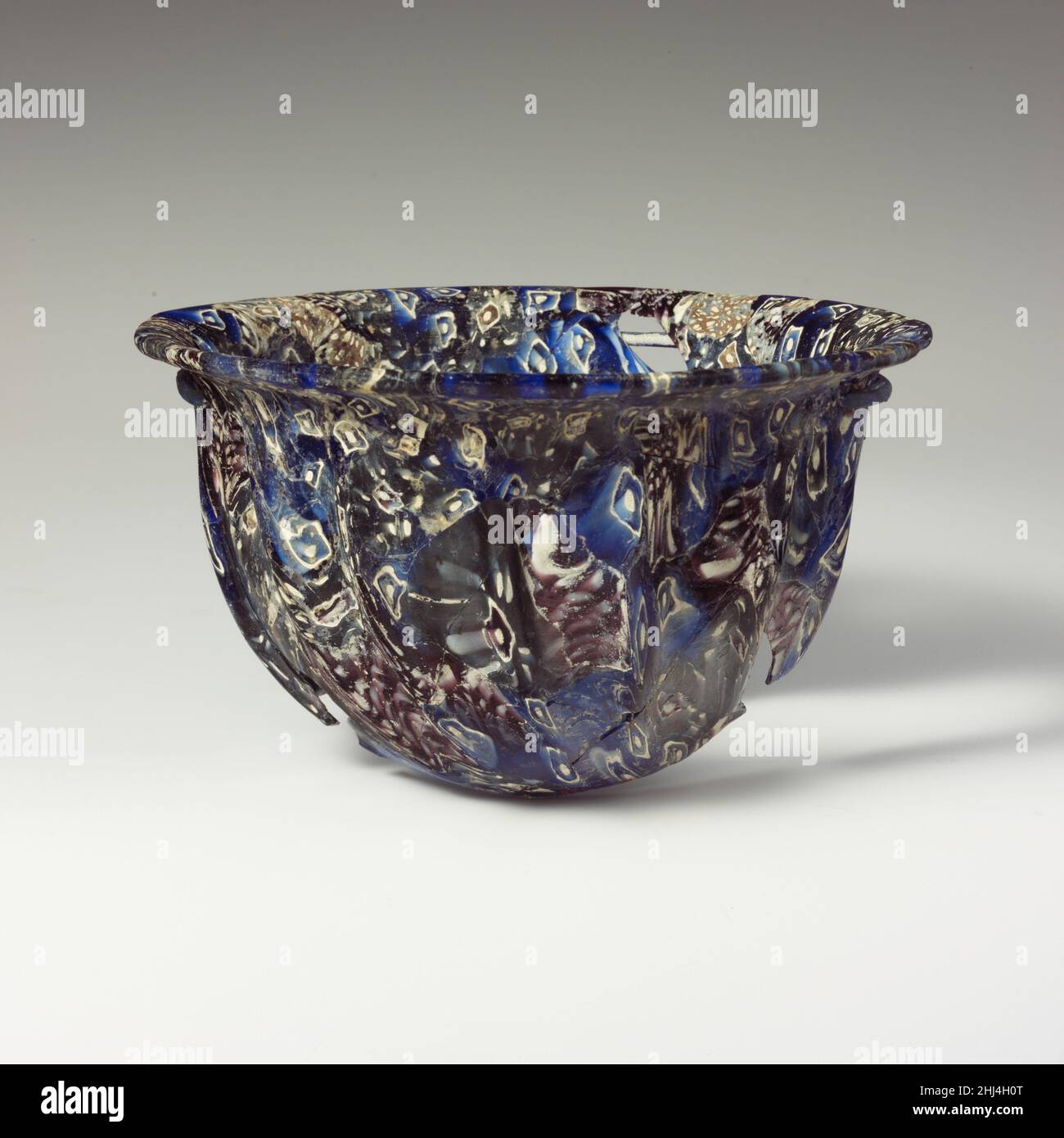 Vaschetta in vetro a mosaico a coste fine 1st secolo a.C.–inizio 1st secolo d.C. romana, probabilmente italiana traslucido blu cobalto e viola, e bianco opaco.bordo orizzontale a cielo strapiombato, con bordo spesso, irregolare, arrotondato; lato curvo convesso, downwards.Composite motivi a mosaico rastremati formati da sezioni poligonali di tre canne: Una su un terreno blu con un quadrato bianco irregolare che circonda un punto bianco centrale; un'altra su un terreno blu con punti bianchi intorno ad un cerchio viola delineato in bianco con un punto bianco centrale; e uno in un terreno viola con un disegno irregolare di punti bianchi; all'esterno, fo Foto Stock