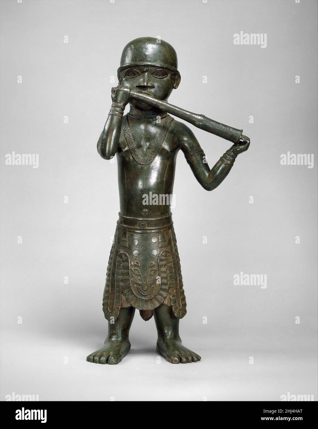 Figura: Horn Player 1550–1680 Edo Peoples nell'arte del Benin, le opere in bronzo possono essere commissionate solo dall'Oba, o regnante, o da altri con il suo permesso. Secondo le tradizioni orali, la tecnica della fusione in bronzo a cera persa fu portata in Benin verso la fine del XIV secolo da Ife, l'antico regno a nord noto per le sue squisite teste commemorative in bronzo fuso. Prima di quel tempo, gli artigiani del Benin producevano ornamenti in bronzo martellato e incisi, ma non fusi. Una volta che la tecnica della fusione a cera persa è stata padroneggiare dagli artigiani del Benin, teste di bronzo e figure bega Foto Stock