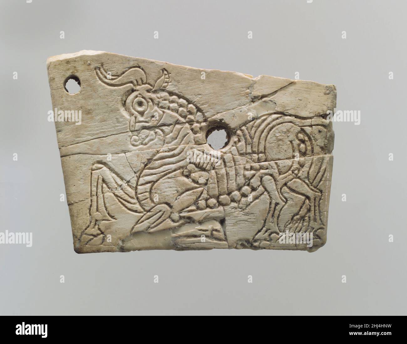 Placca per mobili incisa con un toro inginocchiato ca. 8th–9th secolo a.C. assiro questa placca trapezoidale fu trovata in una stanza che è stata identificata come parte della residenza reale a Fort Shalmaneser, un edificio reale a Nimrud che fu probabilmente utilizzato per conservare tributi e booty raccolti dagli Assiri durante la campagna militare. Gli avori con decorazioni incise come questo sono stati attribuiti ad uno stile assiro simile ai grandi rilievi che costeggiano le pareti del Palazzo Nord-Ovest. Il toro inginocchiato raffigurato su questa placca, con la sua muscolatura stilizzata e l'anatomia finemente incisa, re Foto Stock