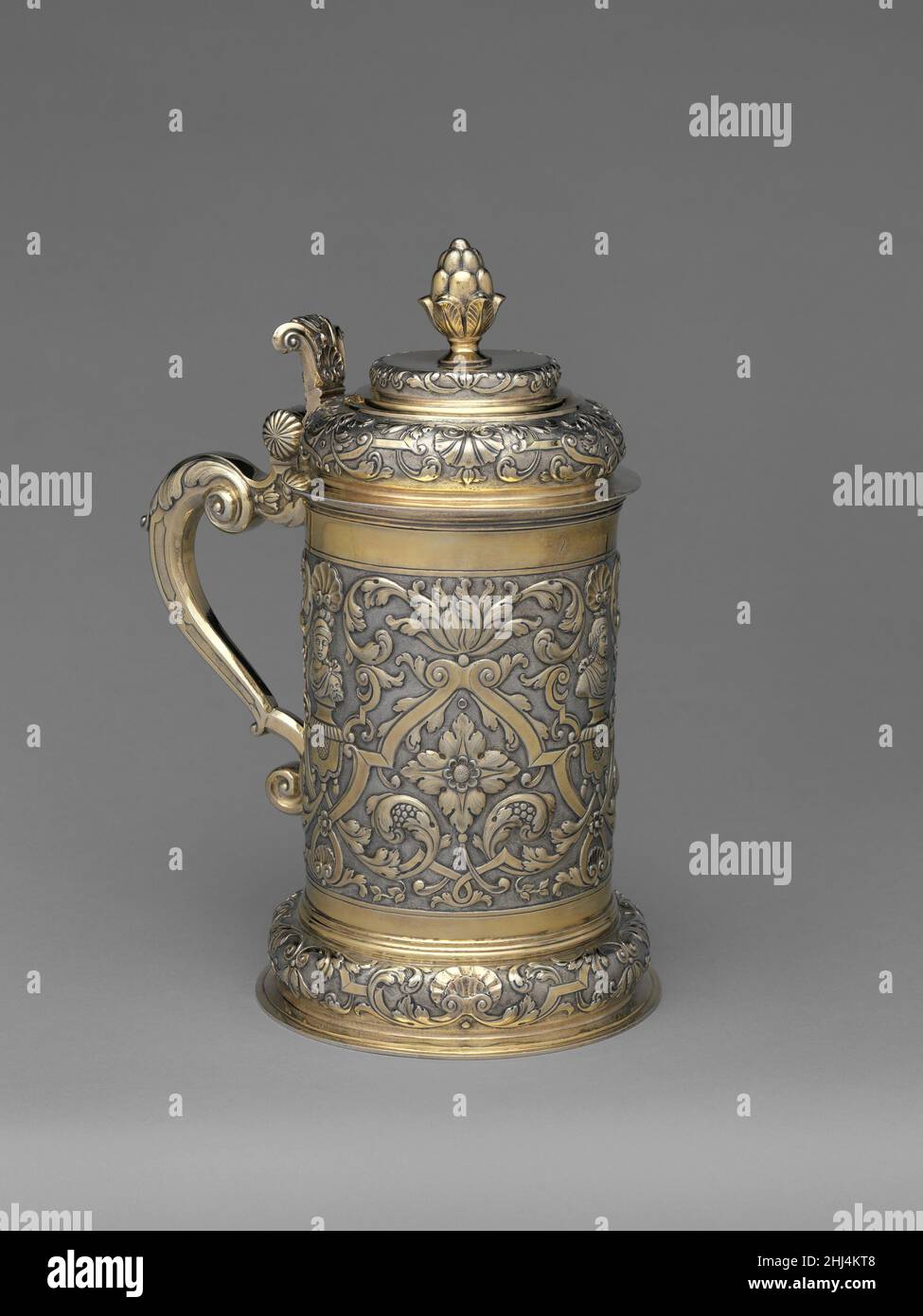 Tankard metà 18th secolo Michael maggio II questo tankard elegantemente proporzionato, dorato è un tardo esempio del suo tipo. Il costruttore, che faceva parte di una ben nota dinastia di orafi, applicò una decorazione armoniosa di tele tardo barocche circondando tre basi imitando brevi tratti di drappeggi decorativi, detti lambrequins, ciascuno supportando un antico busto. Un finale pinecone in ghisa sormonta il coperchio a doppia cupola come un monumento in miniatura.LiteratureImportant Argento. Sale Cat., Sotheby’s, New York, 7 aprile 1987, n.p., n. 40.Judit H. Kolba. Argento Ungherese: La Collezione Nicolas M. Salgo. L Foto Stock