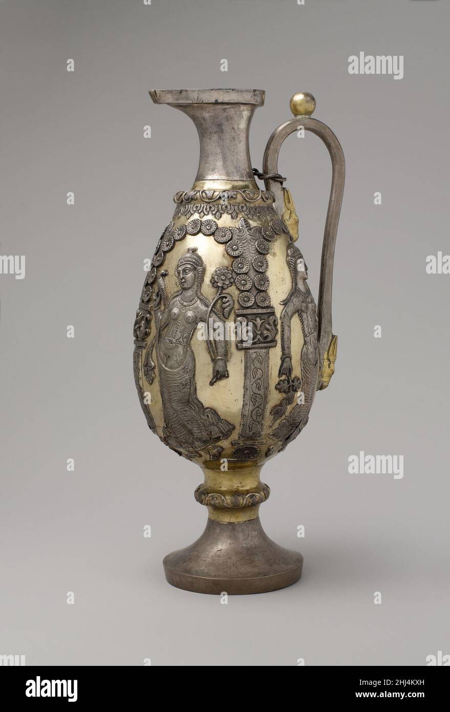 Pecore con danze femmine all'interno di portici ca. I vasi d'argento Sasaniani di fine Sassania del 7th-6th secolo d.C., in particolare bottiglie e ewers, sono stati spesso decorati con figure femminili che tenevano una varietà di oggetti festali. L'aspetto di questi motivi testimonia la continua influenza dell'immaginario greco associato al dio vino Dioniso. Su questa nave dorata in argento, archi floreali, sorretti da bassoriliaste, incorniciano quattro figure femminili danzanti. Ognuno contiene un oggetto cerimoniale in entrambe le mani: Rami di uva e foglia, un vaso, un fiore a forma di cuore. Sotto un portico, gli uccelli si picchiano alla frutta, e beneat Foto Stock