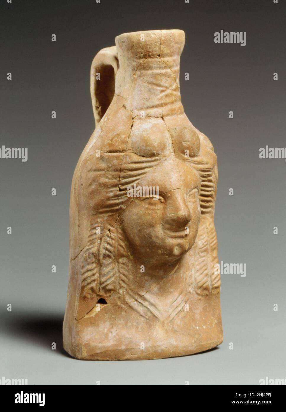 Fiasca a testa di terracotta ca. 80–1 a.C. Greco, probabilmente cipriota il pigmento rosso lucido che ricopre la superficie di questa fiasca di impugnatura lo identifica come un esempio di Magenta ware. La combinazione del viso modellato, del collo a ruota, del dorso e della base formati a mano, è anche caratteristica di questa classe di ceramiche. Anche se la ceramica di Magenta è stata fatta in tutto il mondo mediterraneo, fiasche maneggiate nella forma delle teste umane sono state trovate più comunemente su Cipro. Fiasca a testa di terracotta 240128 Foto Stock