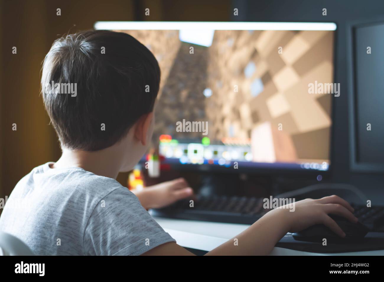 Il ragazzo gioca la minecraft. Giochi per computer a casa. Costruzione sotto forma di gioco. Giochi per bambini e computer. Processo di gioco. Gestione in minecraf Foto Stock