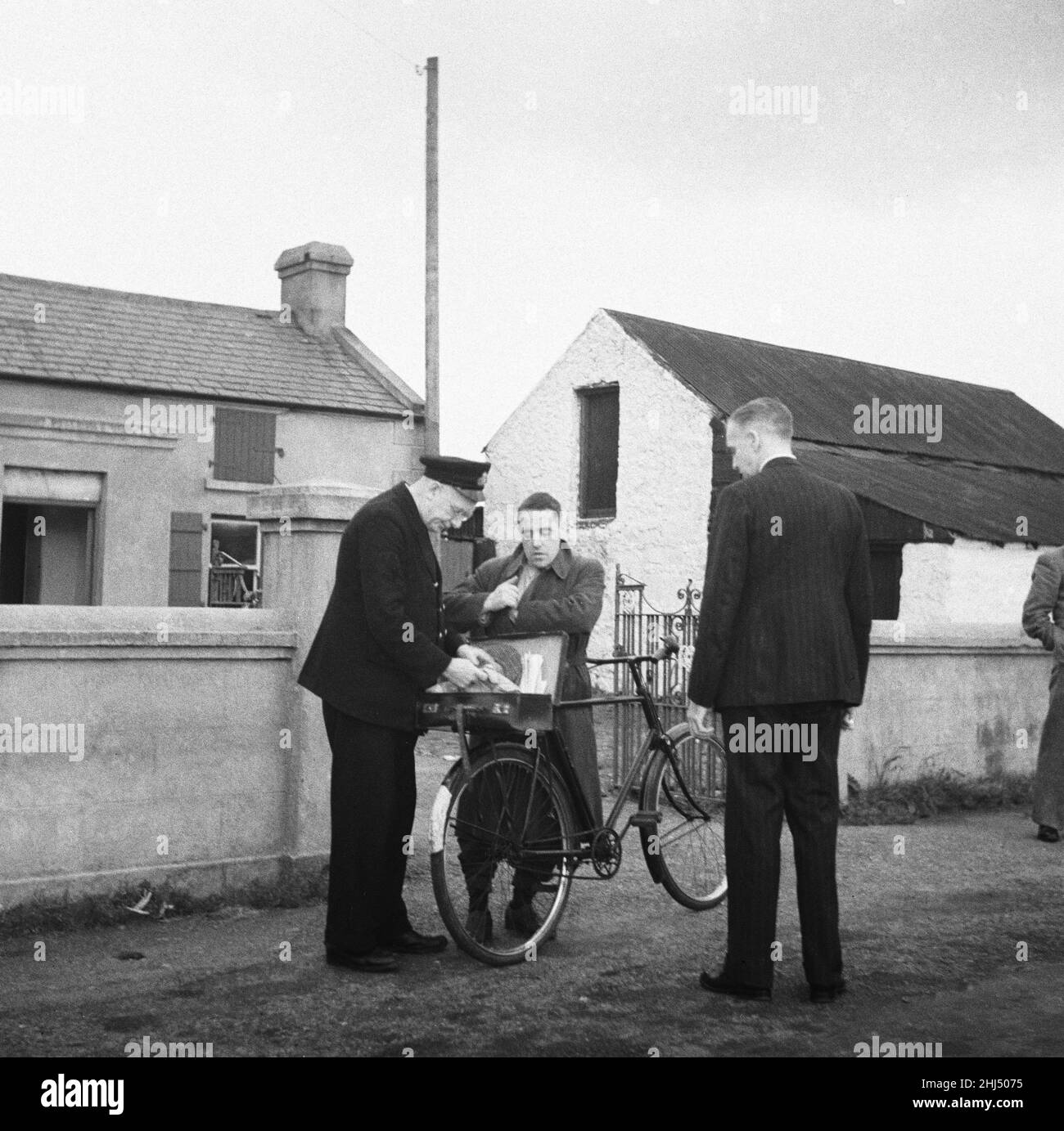 Ufficiale doganale che controlla i documenti di un uomo in bicicletta presso la posta di frontiera tra l'Irlanda del Nord e la Repubblica. Circa 1960. Foto Stock