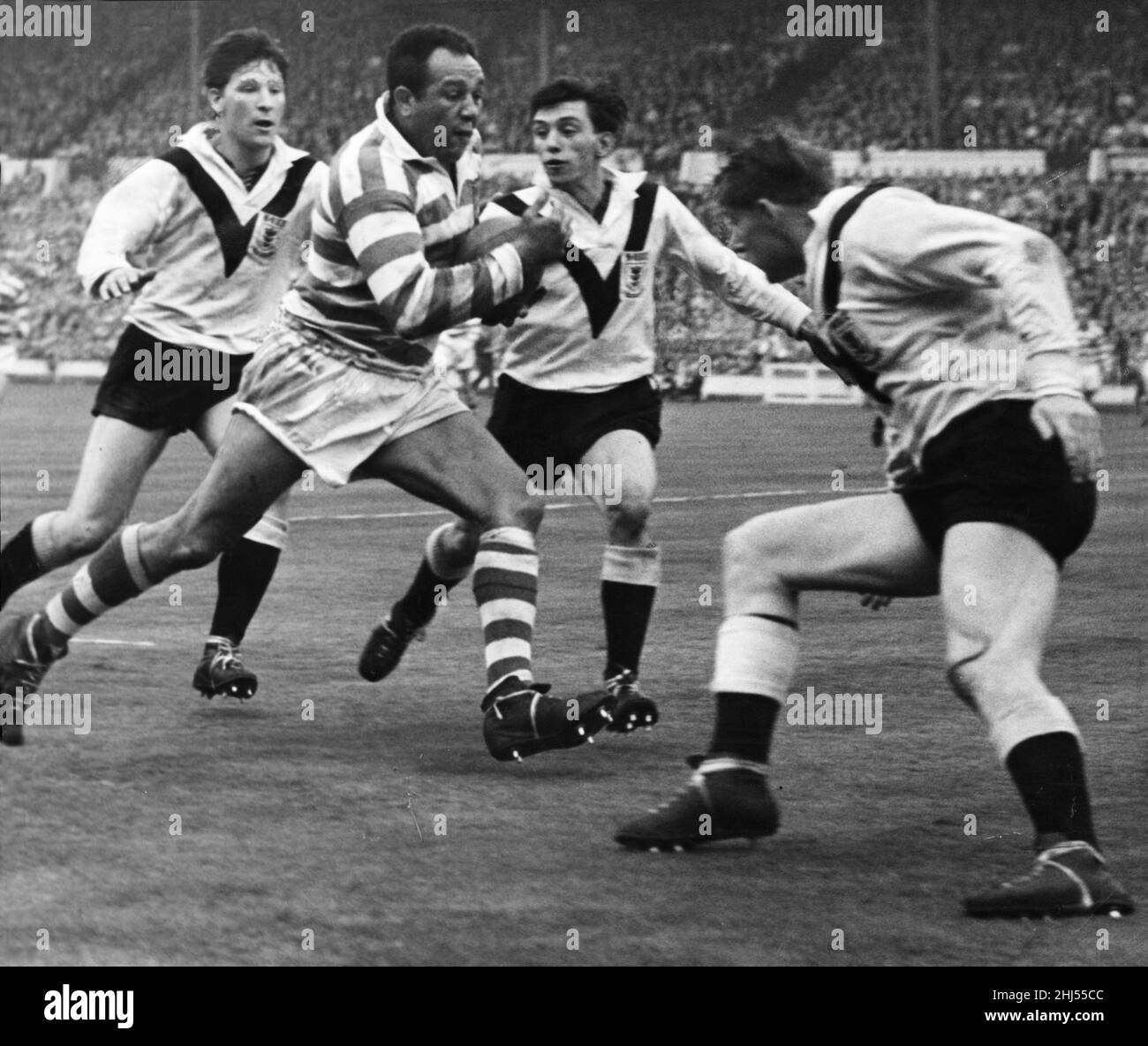 Azione durante lo scontro della Rugby League tra Wigan e Hull durante la finale della Challenge Cup al Wembley Stadium. Immagini mostra: Tre uomini squadra fino a fermare il giocatore di Wigan Billy Boston mentre cerca di bulldoze la sua strada attraverso la linea di prova di Hull. Wigan è andato avanti a vincere 30 - 13 con Boston che ha segnato due mete. 9th maggio 1959. Foto Stock