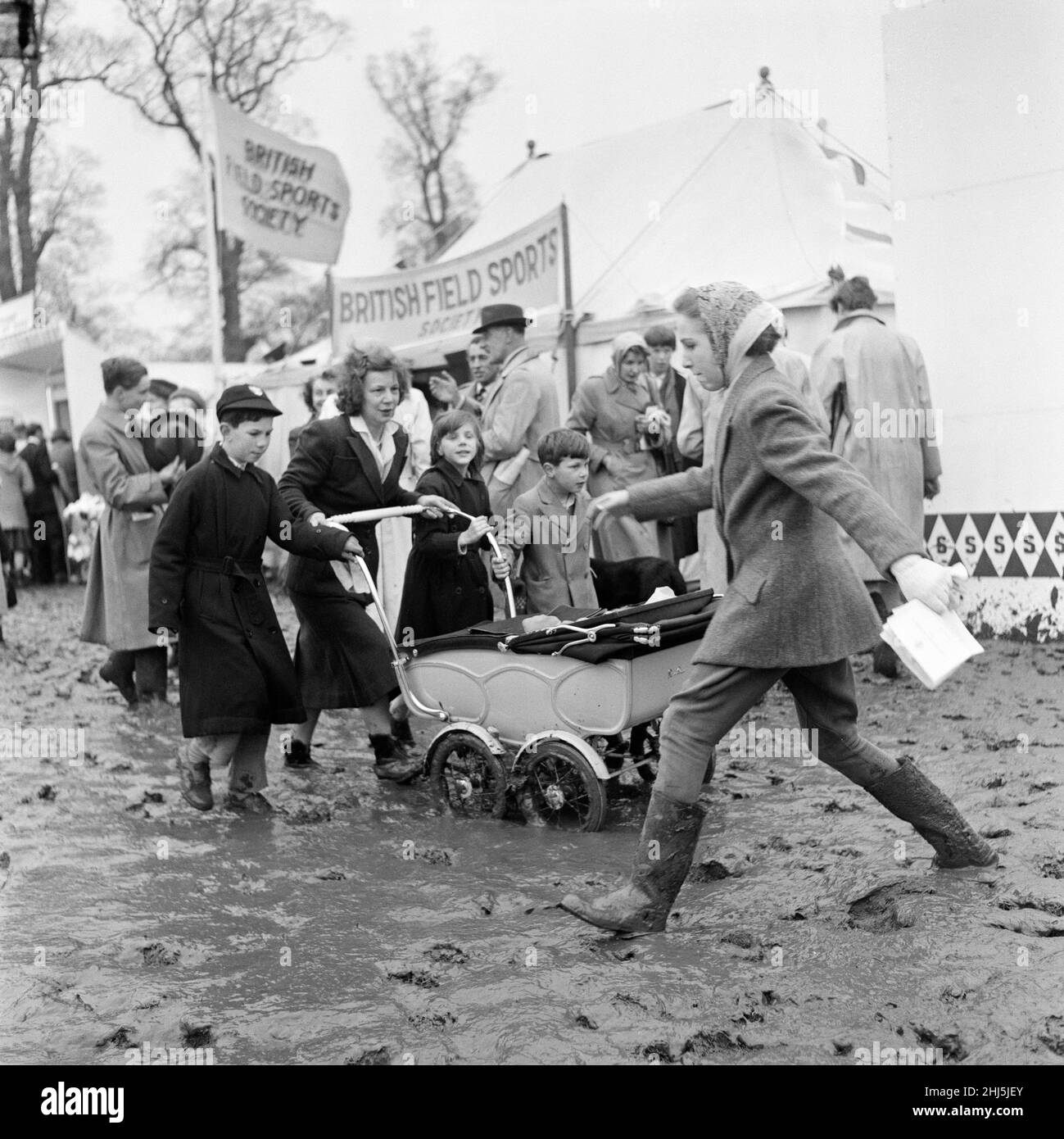 Prove a cavallo di badminton, Badminton, Gloucestershire. Una donna che spinge un agram attraverso un campo fangoso. 17th aprile 1959. Foto Stock