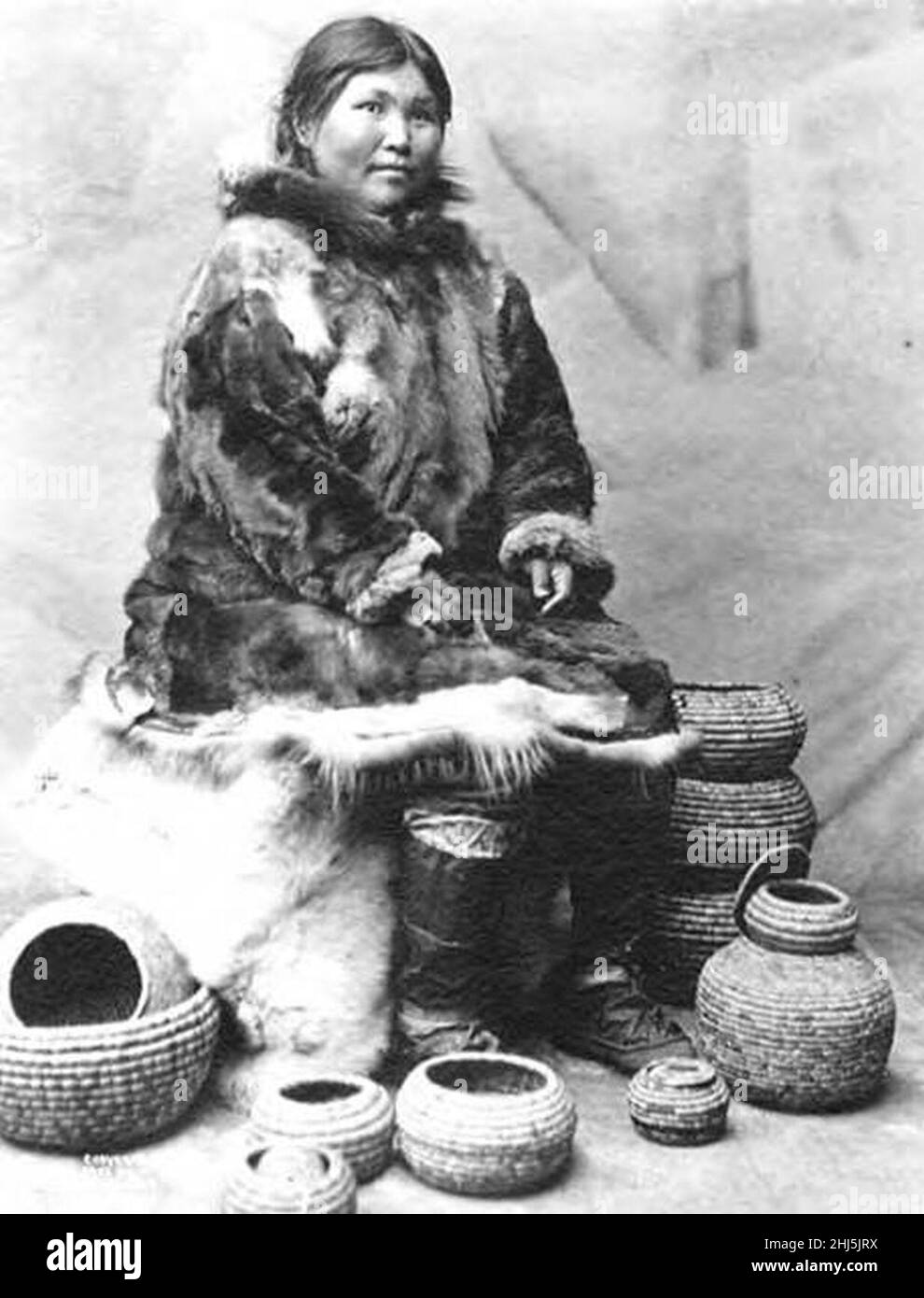 Ritratto studio di Eskimo donna vestito in parka di pelliccia d'alce con stivali vescica di sigillo seduti con diversi cestini a spirale, Nome, 1903 (al+CA 6507). Foto Stock