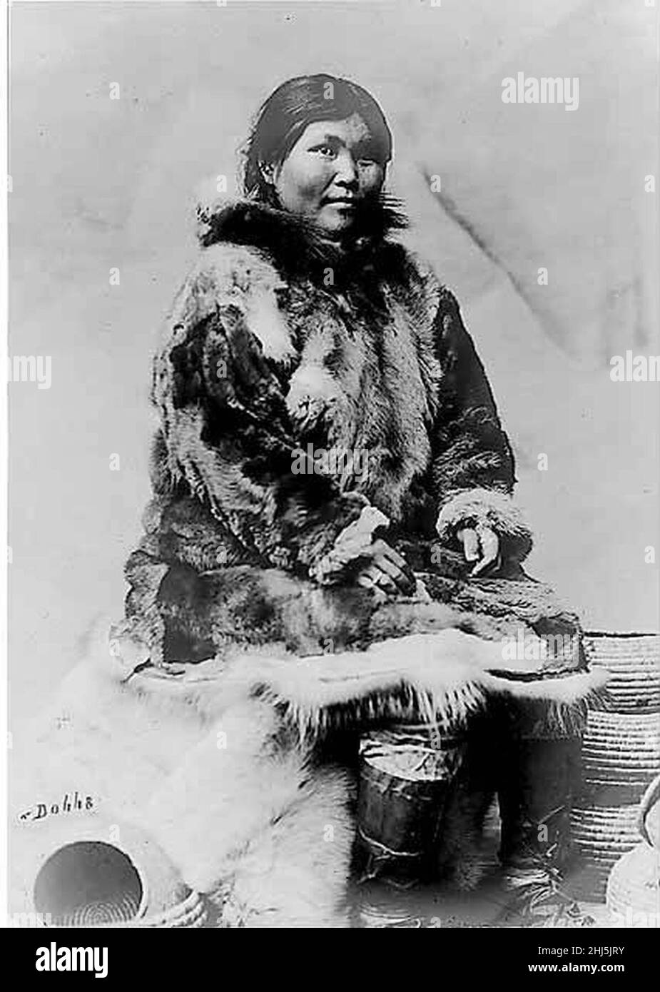 Ritratto studio di donna Eskimo con tatuaggio mento che indossa parka in pelle di alce e stivali vescica di sigillo, seduta accanto a diverse bobine (al+CA 39). Foto Stock