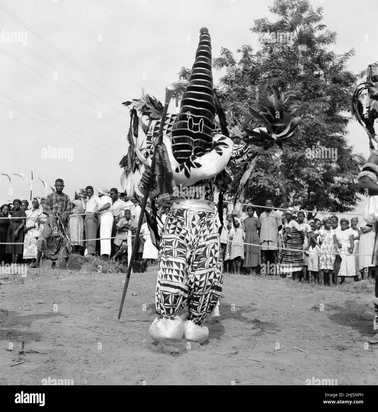 Ballerino nigeriano che si esibisce in costume tradizionale per la regina Elisabetta II e il duca di Edimburgo durante il loro tour in Nigeria. Febbraio 1956. Foto Stock