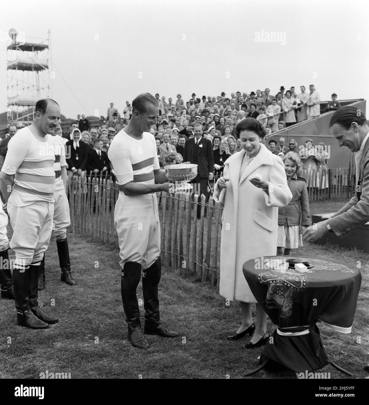 La Regina Elisabetta II presenta al marito, il Principe Filippo, Duca di Edimburgo, la Victoria Cup durante l'intervallo al polo di Windsor Great Park, seguito dalla Principessa Anne. Il principe Filippo ha giocato per le Guardie gallesi, che hanno battuto i gol Silver Keys 3,5 a 3 gol. 17th maggio 1959. Foto Stock