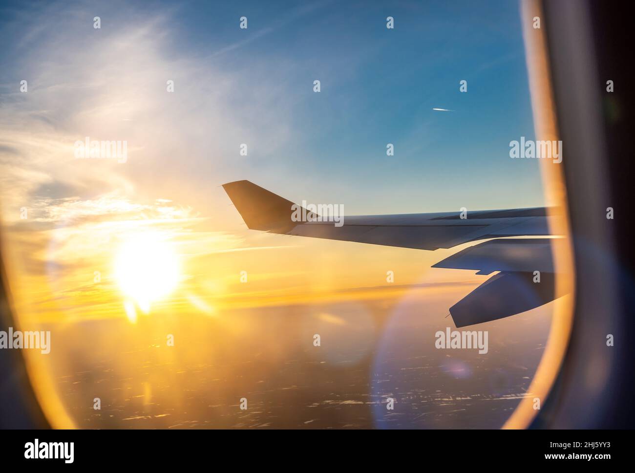 Volando e viaggiando, vista dalla finestra dell'aeroplano sull'ala all'ora del tramonto. Ala di aerei sotto la terra e le nuvole. Viaggi, turismo, vacanze, settimana Foto Stock