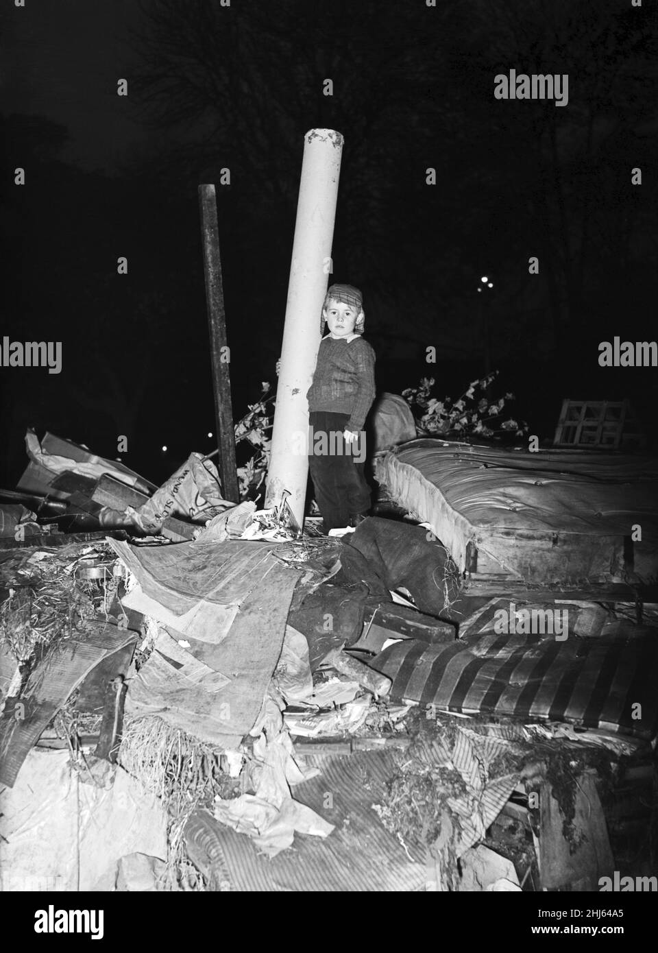 Il falò che i bambini di Windsor avevano costruito sull'Acre di Batchelor per la notte di Guy Fawkes fu bruciato dai Guardsmen. Nella foto, Richard di cinque anni armato con un grande tubo di cartone si alza guardia in cima al falò, mentre altri bambini sono alla ricerca della città per più carburante per rifornire. Windsor, Berkshire. 28th ottobre 1957. Foto Stock