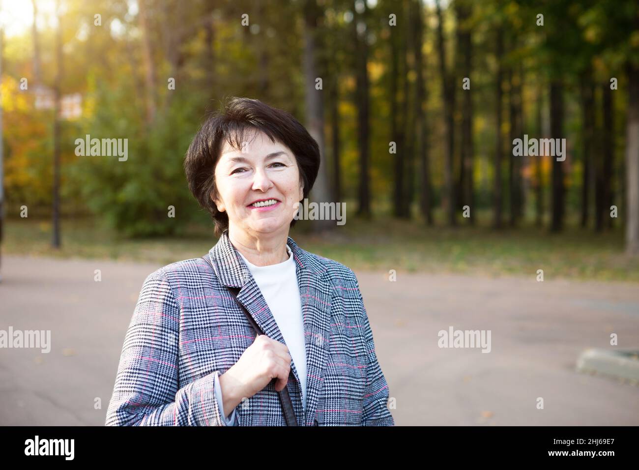 Ritratto di una senora felice per 50 anni nel parco in autunno in una giacca grigia. Foto Stock