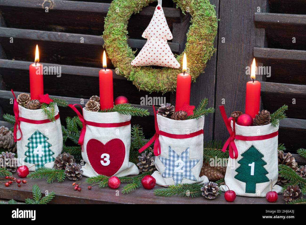 decorazione natalizia con candele rosse d'avvento in sacchi, coni e rami di abete Foto Stock