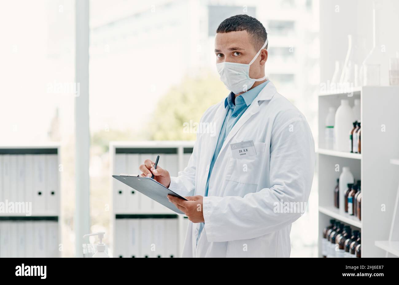 Il conto alla rovescia per una svolta del Covid-19. Ritratto di un giovane scienziato che scrive note su una clipboard in un laboratorio. Foto Stock