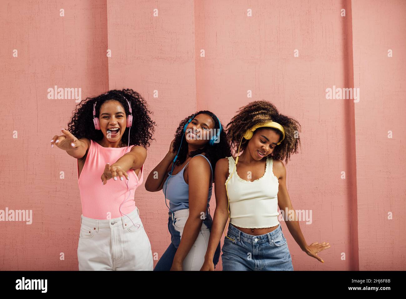 Gruppo di giovani donne che ballano insieme mentre ascoltano musica con le cuffie Foto Stock