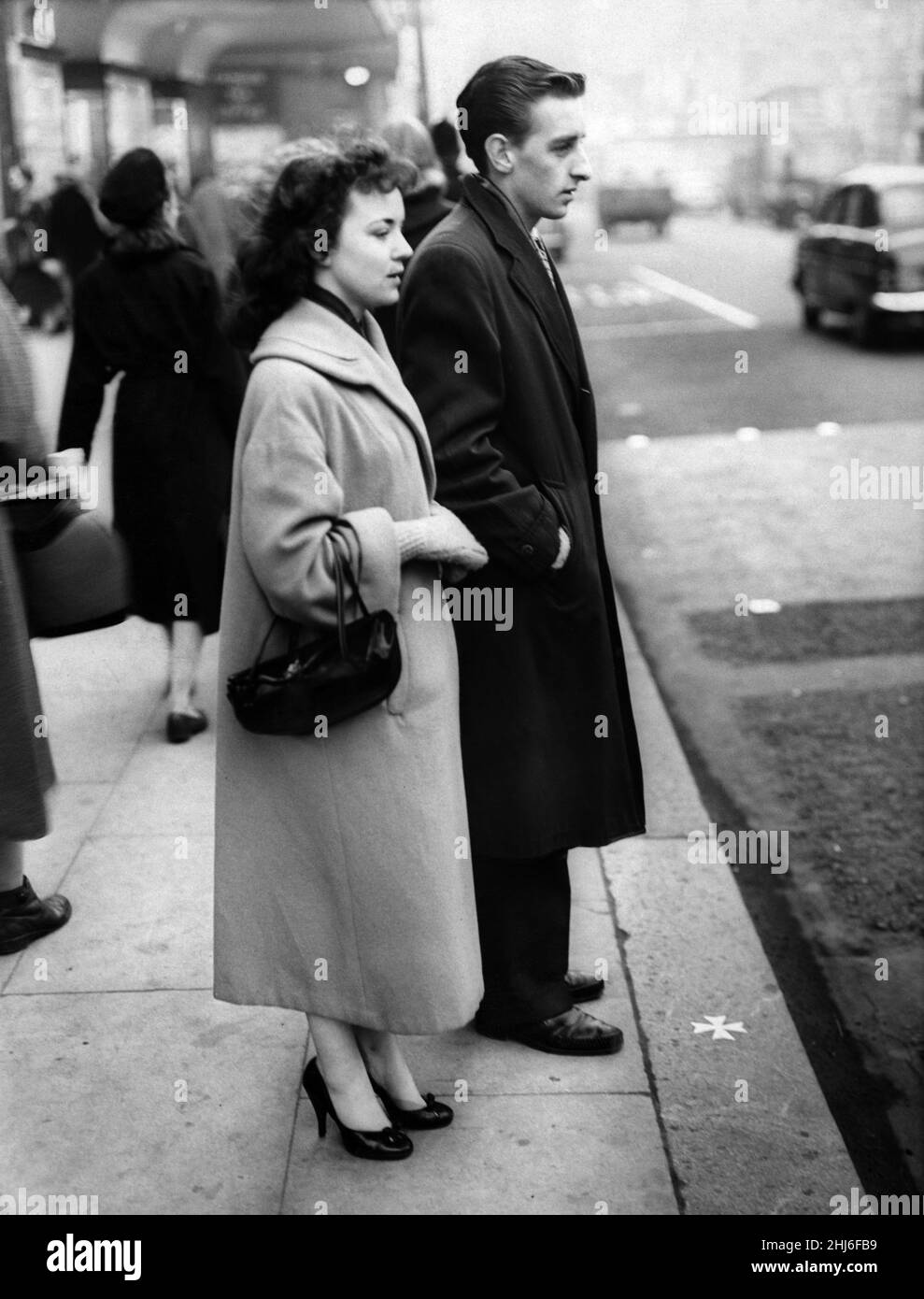 Una giovane coppia si trova sul sito dell'altare della Chiesa di San Pietro. Ai loro piedi c'è una croce di ottone inset sul marciapiede. Liverpool, Merseyside. Maggio 1959. Foto Stock