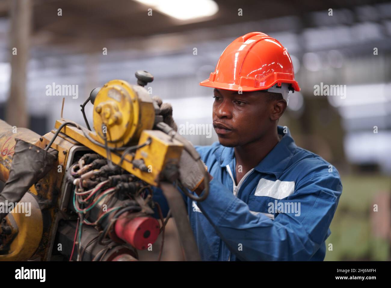 Ritratto di tecnico / lavoratore di industria pesante professionale che indossa uniforme di sicurezza, occhiali e cappello rigido. In background non focalizzato grande industriale F Foto Stock