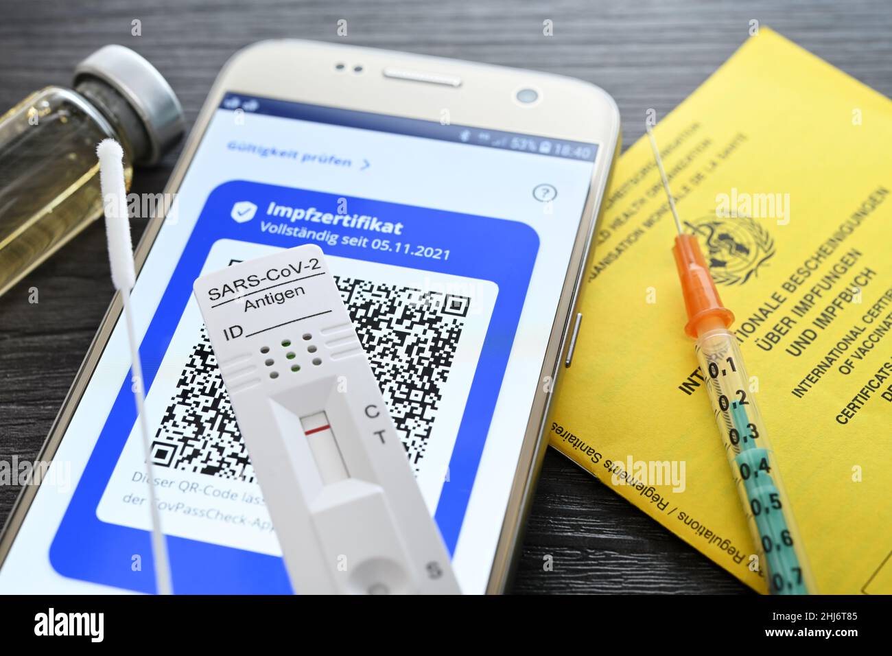 Impfzertifikat auf smartphone mit negativem Corona-Schnelltest, Impfausweis und Impfspritze, Symbolfoto digitaler Impfnachweis und 2G+-Regel Foto Stock