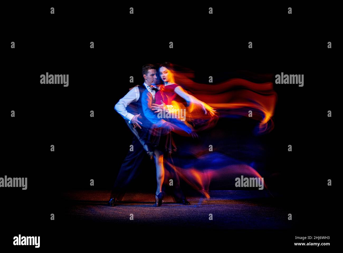 Ritratto dinamico di giovani ballerini da ballo tango argentino isolato su sfondo scuro con luce mista al neon. Foto Stock