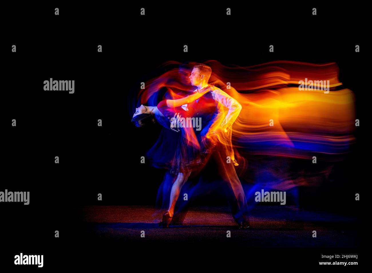 Ritratto dinamico di giovani ballerini da ballo tango argentino isolato su sfondo scuro con luce mista al neon. Foto Stock