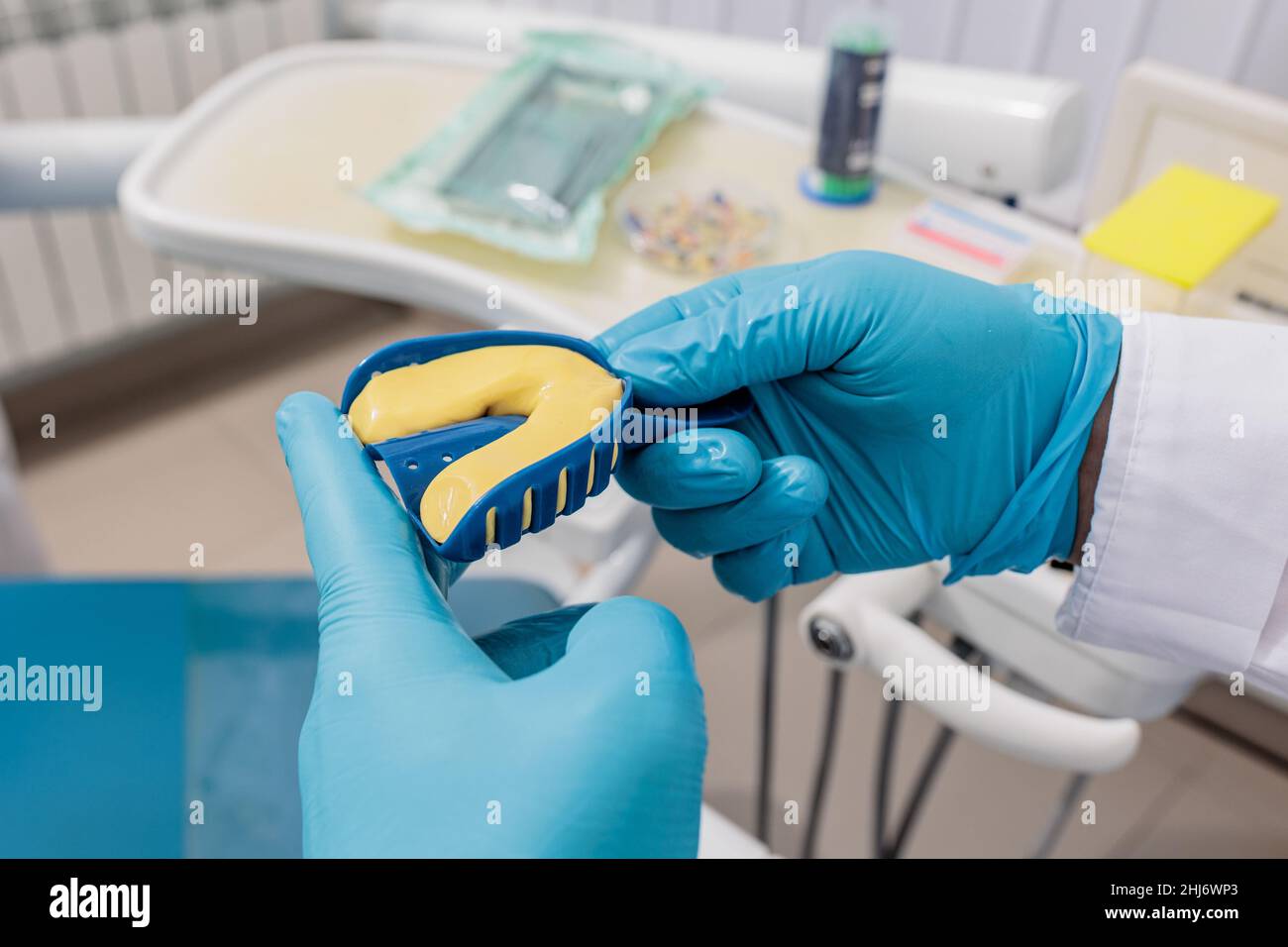 il dentista che indossa guanti protettivi spreme la massa nell'articolatore con la muffa dei denti. Foto Stock