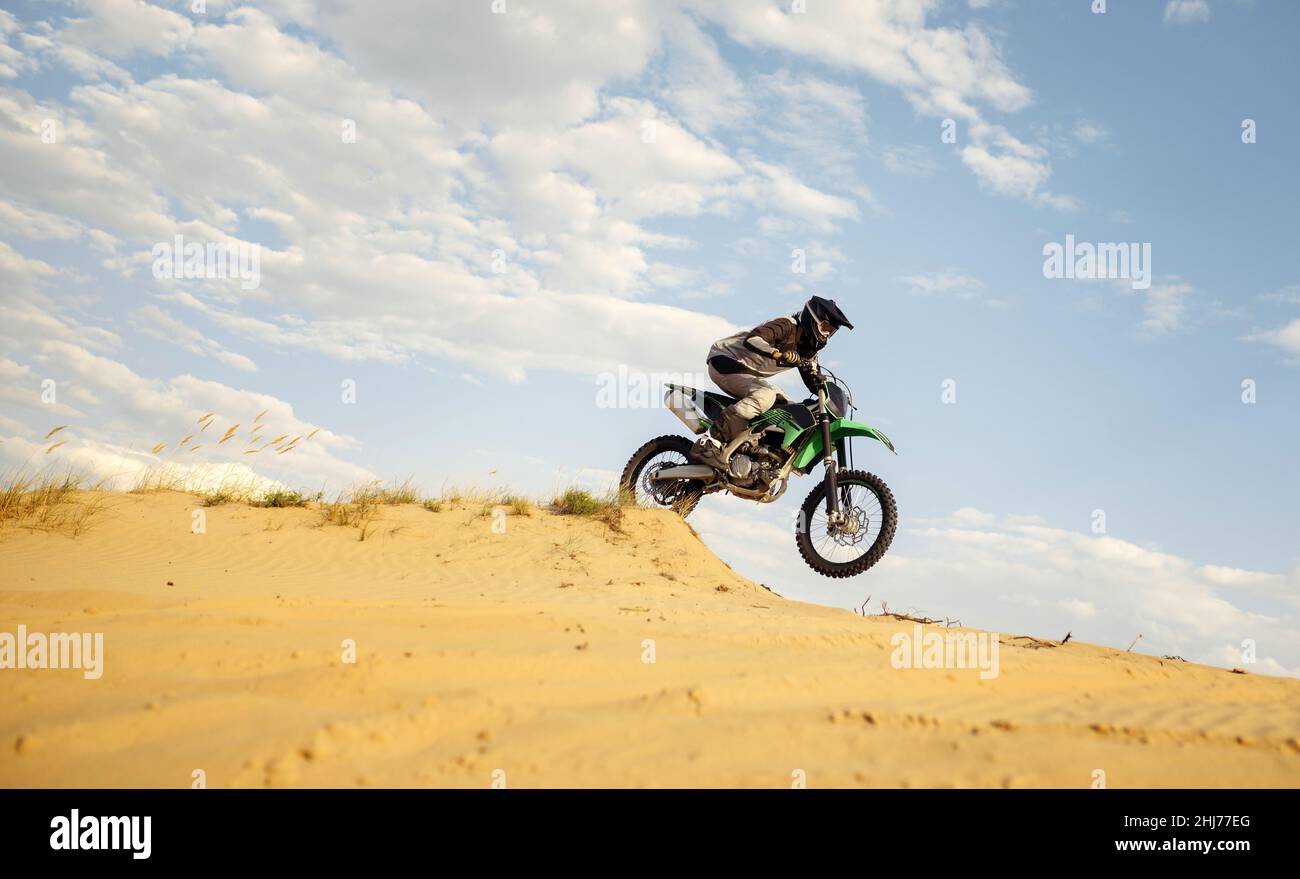Motociclista professionista che scivola su una collina di sabbia Foto Stock