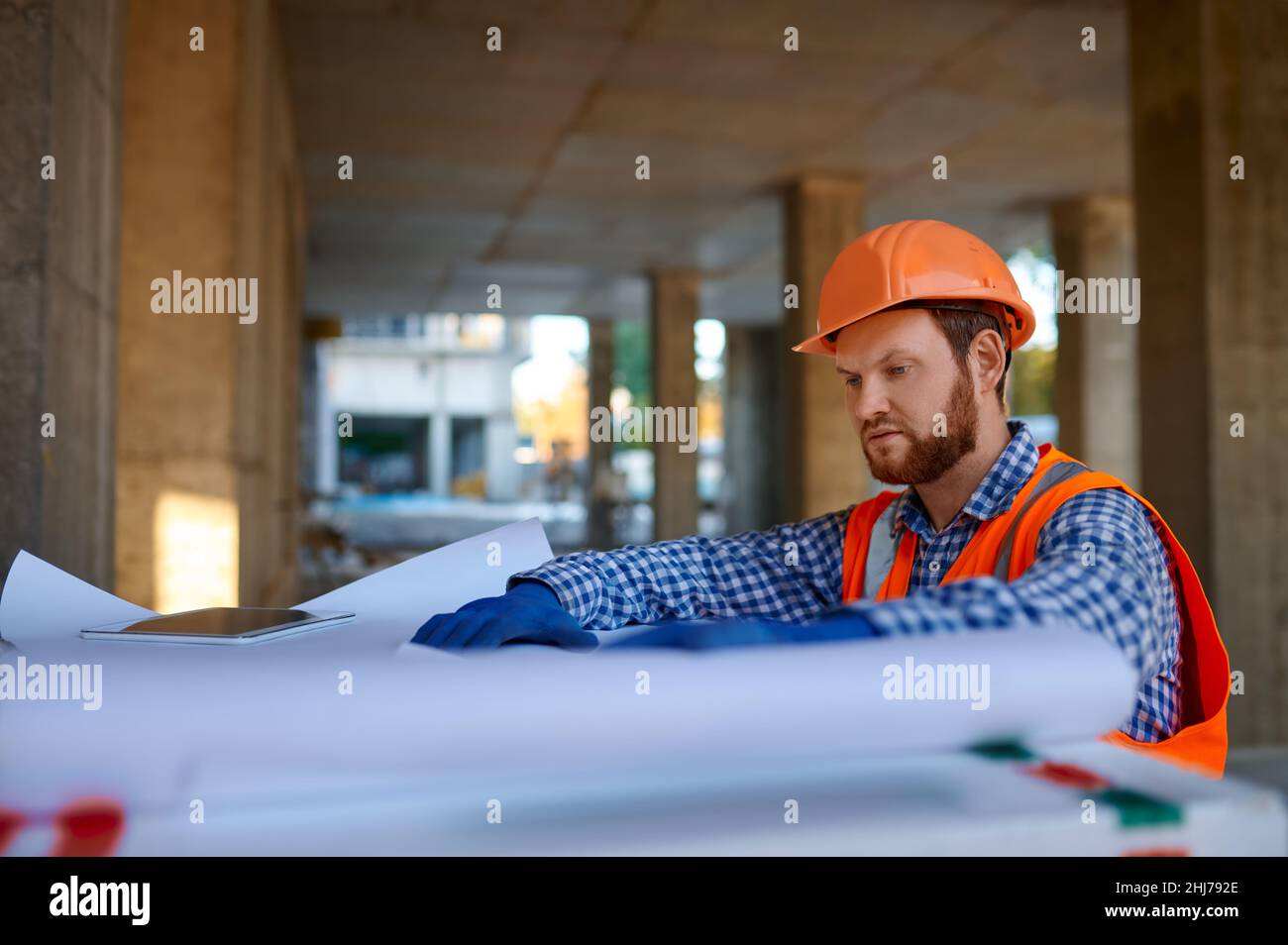 Appaltatore che utilizza un tablet digitale in cantiere Foto Stock