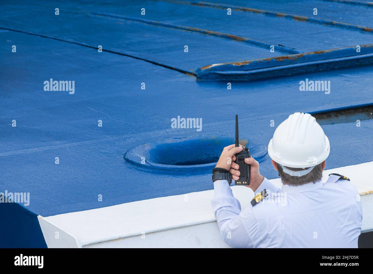Marinaio adulto con un casco che tiene un walkie-talkie su una nave in Grecia Foto Stock