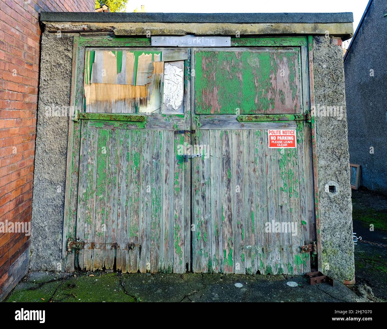 Garage dilatati con porte in legno verde e verniciatura peeling Foto Stock