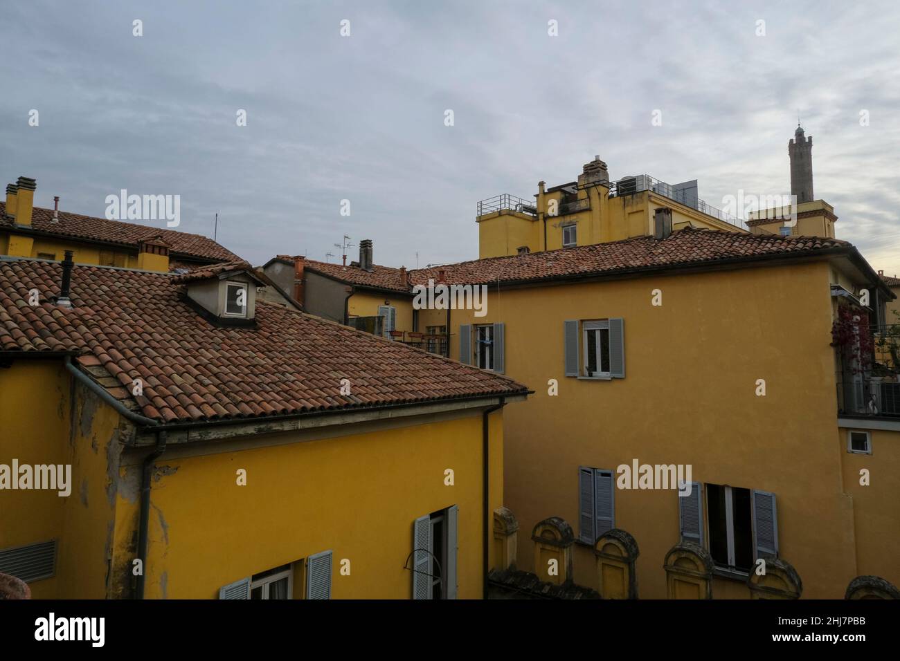 vista sui tetti di tegole rosse di case gialle e palazzi arancioni nella città attraverso il cielo serale. Sfondo della città. Architettura italiana Foto Stock