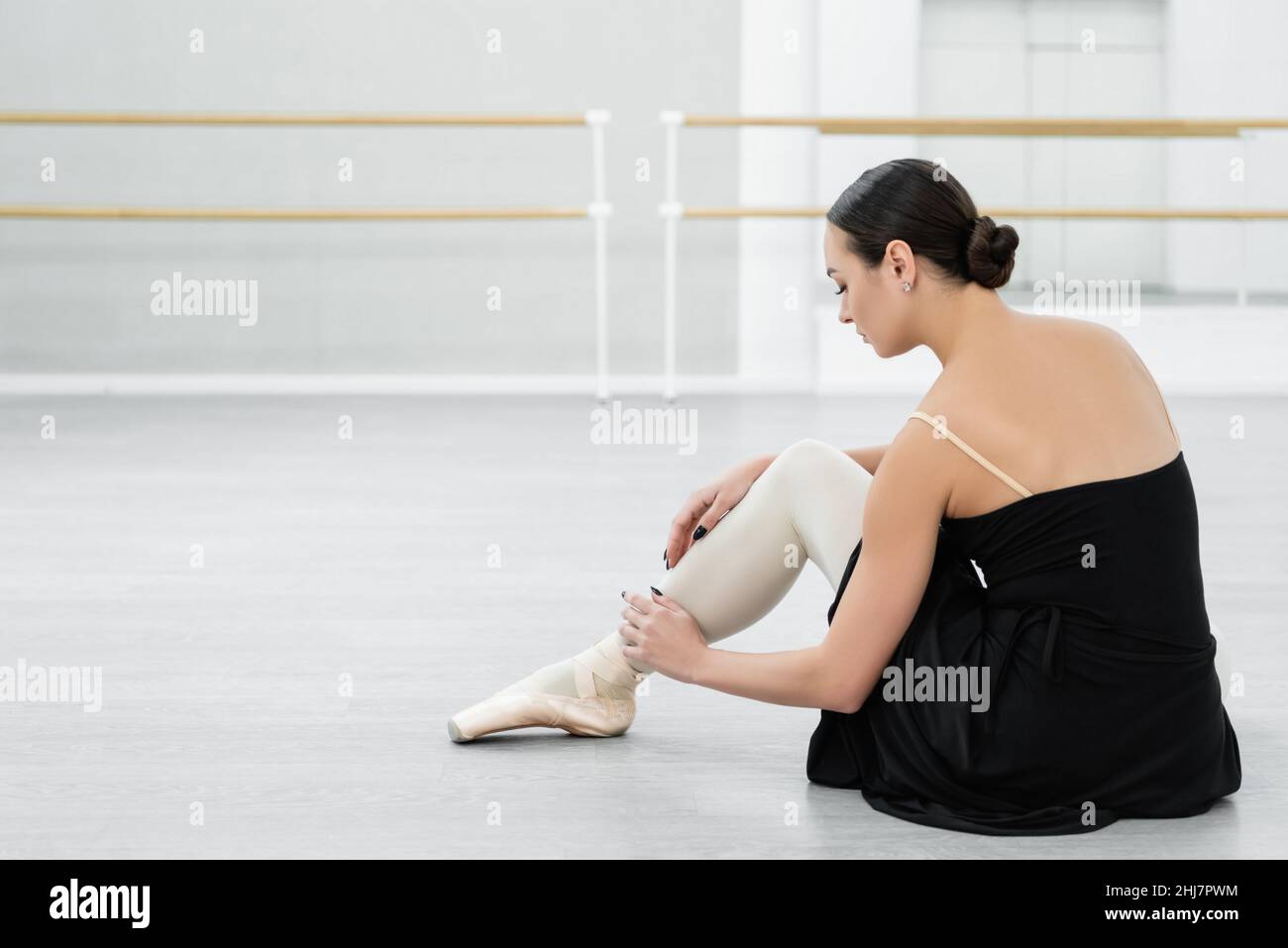 bruna ballerina con punta regolabile mentre si siede sul pavimento in studio Foto Stock