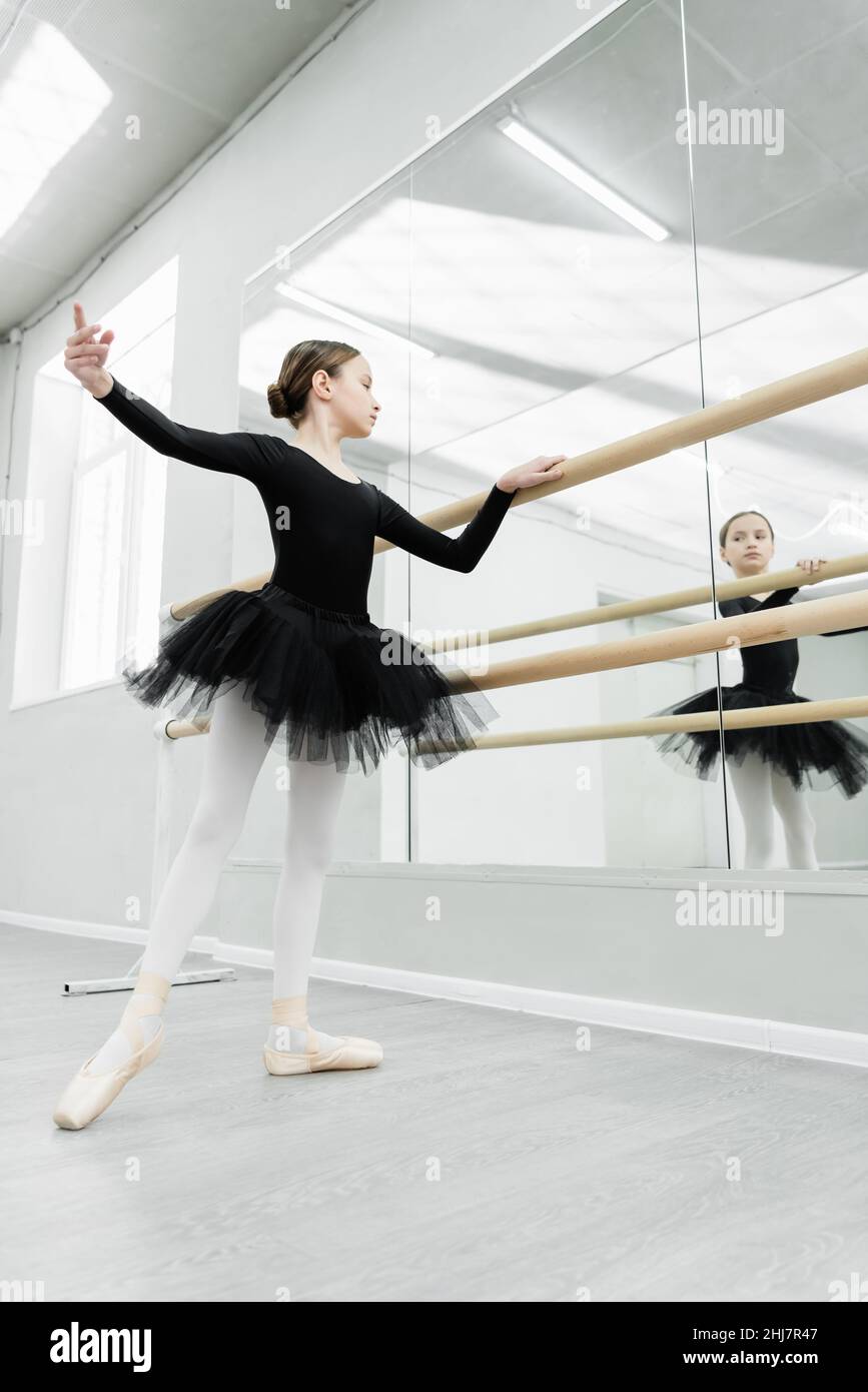 bambino in tutu nero guardando nello specchio durante la ripetizione in studio balletto Foto Stock