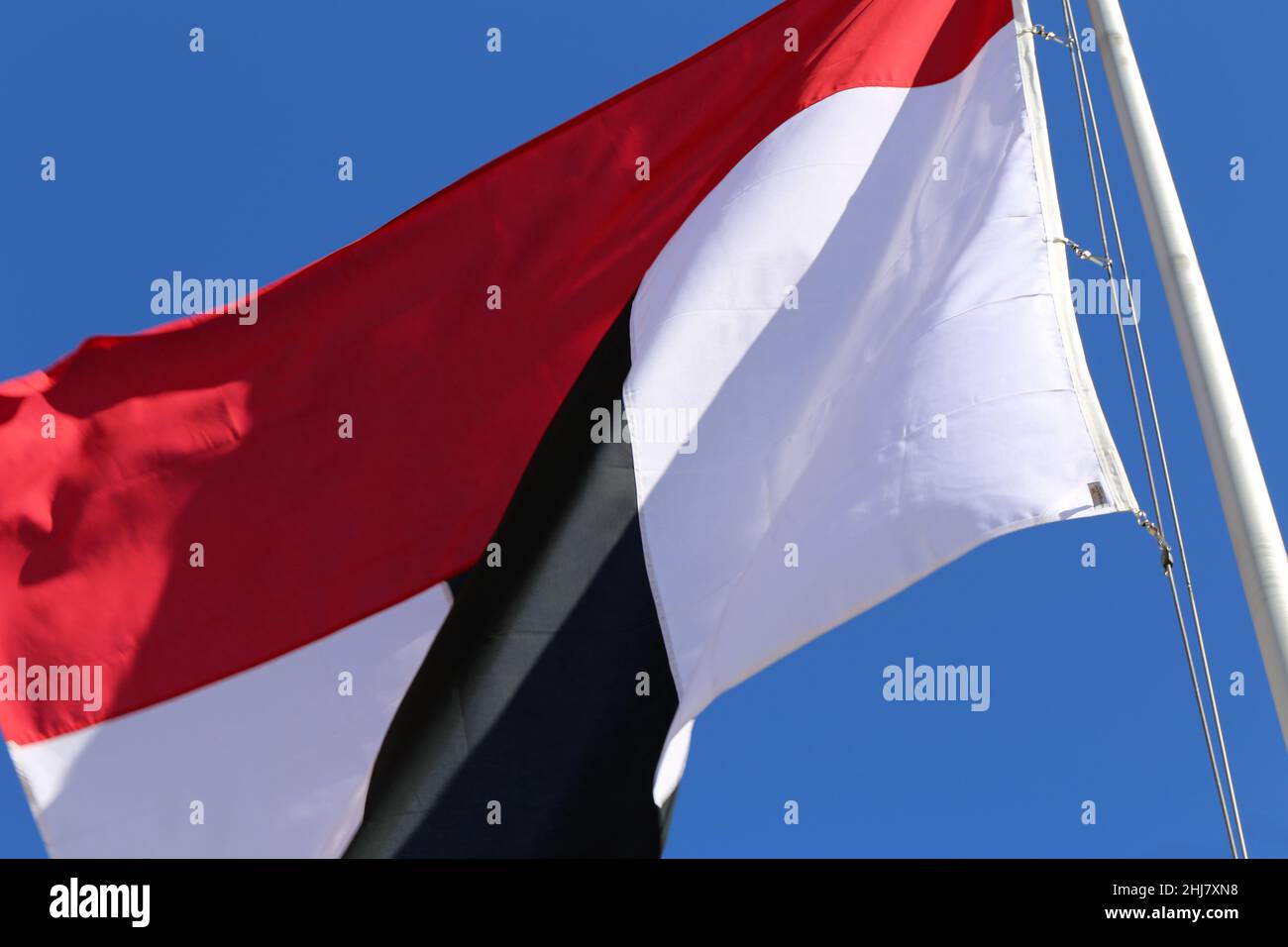 Bandiera rossa, bianca e nera che ondita nel vento. Fotografato durante una giornata estiva di sole in Svizzera. Cielo blu sullo sfondo. Foto Stock