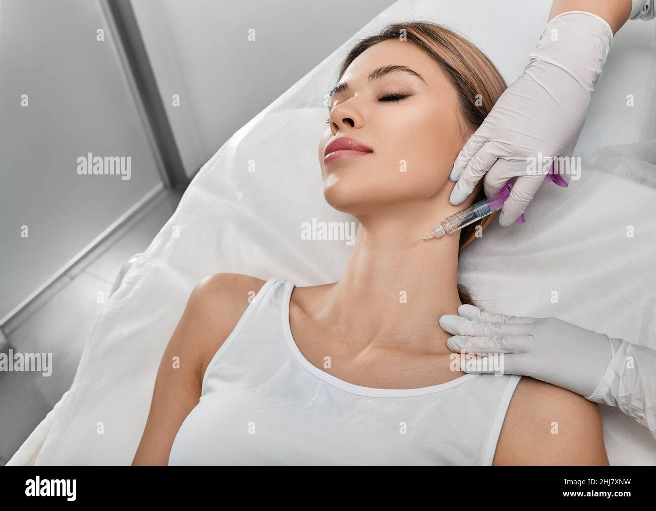 Lisciare la pelle del collo femminile con iniezioni nel collo presso la clinica cosmetica. Ringiovanimento e contornazione della pelle del collo, mesoterapia e biorevitalizzazione Foto Stock