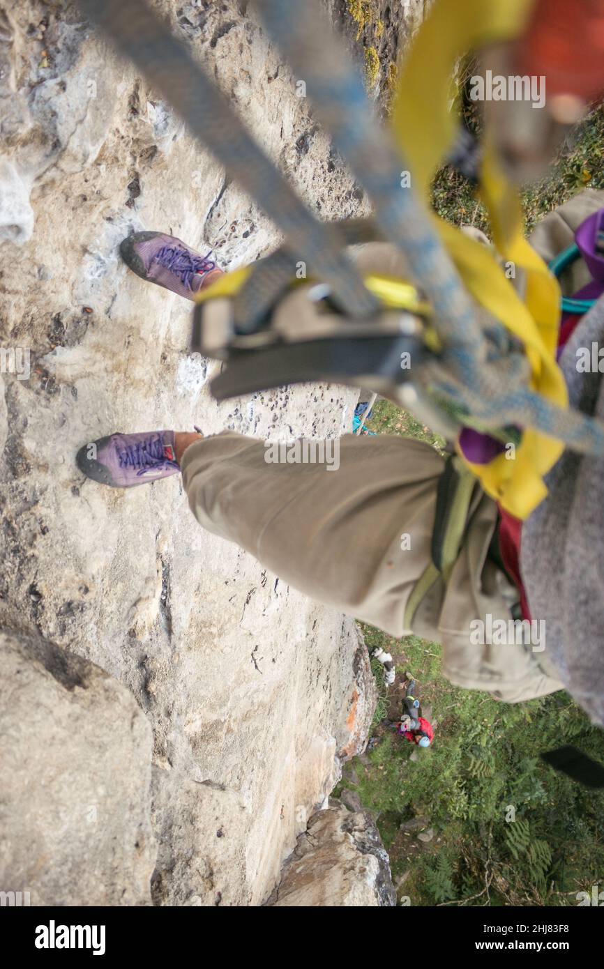 POV: Scalatore di roccia appende dalla corda e dall'ingranaggio alto sopra il terreno Foto Stock