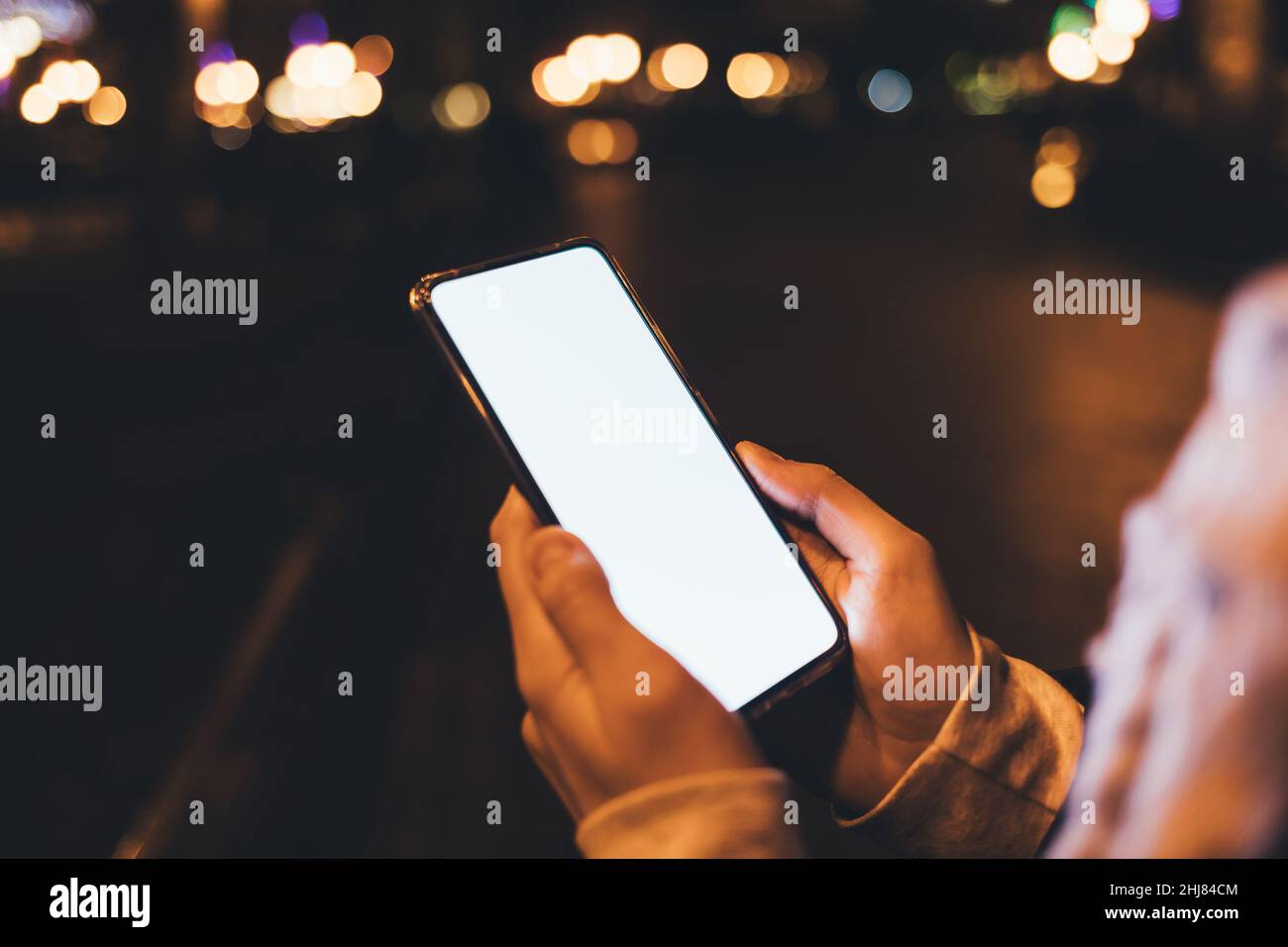 Smartphone close-up con display vuoto in mani femminili all'aperto di notte in città Foto Stock