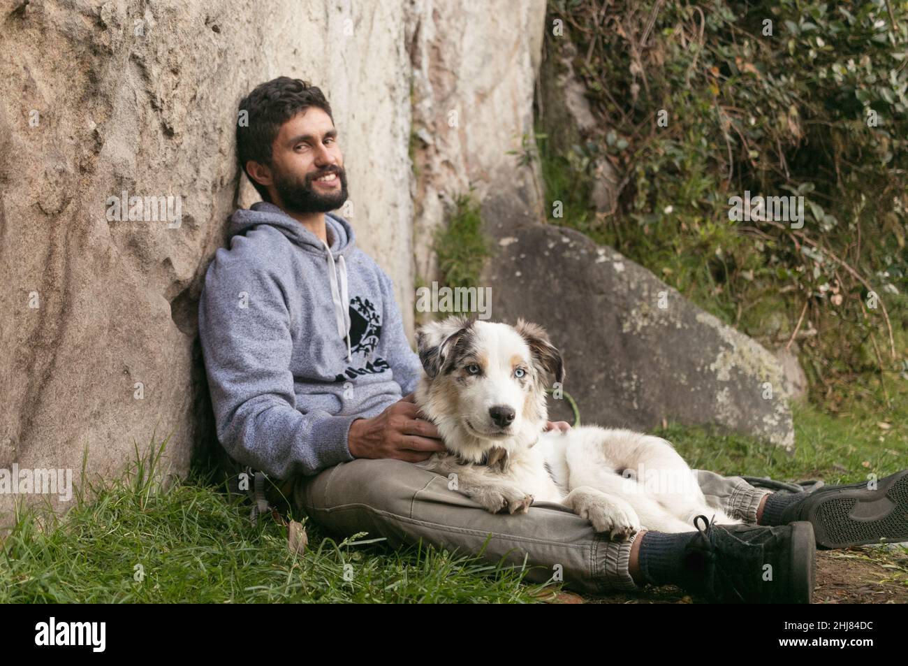 L'uomo ispanico e le collie di bordo marroni si amano all'aperto Foto Stock