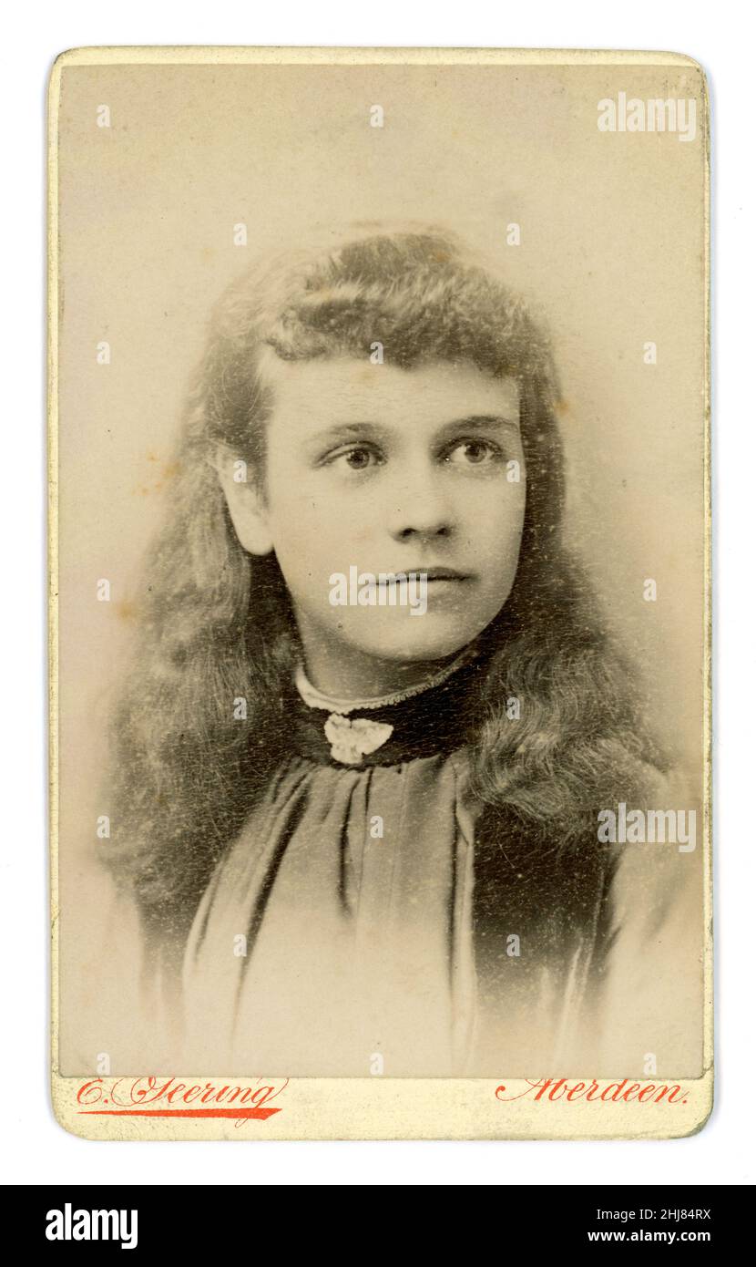 Carte de visite (CDV) dell'epoca vittoriana originale della graziosa ragazza vittoriana della classe media scozzese con i capelli lunghi, spilla sullo scollo della camicetta, dallo studio fotografico di E. Geering, Aberdeen, Scozia, Regno Unito circa 1885. Foto Stock