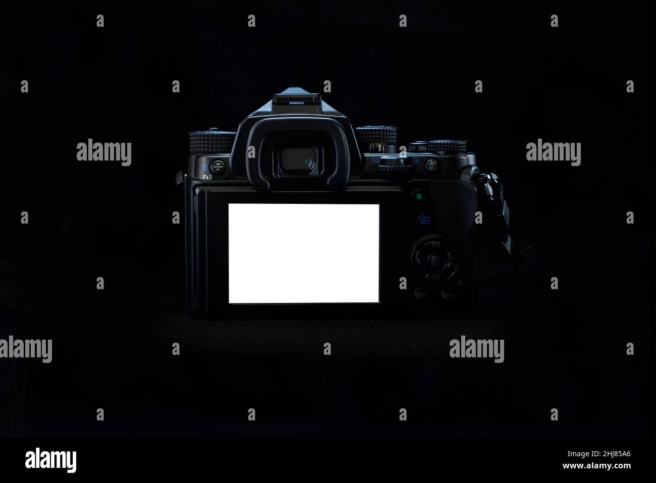 Luce a tasti bassa, lato posteriore di una DSLR con corpo nero su sfondo nero, che mostra lo schermo LCD in bianco con luce arim sulla parte superiore Foto Stock