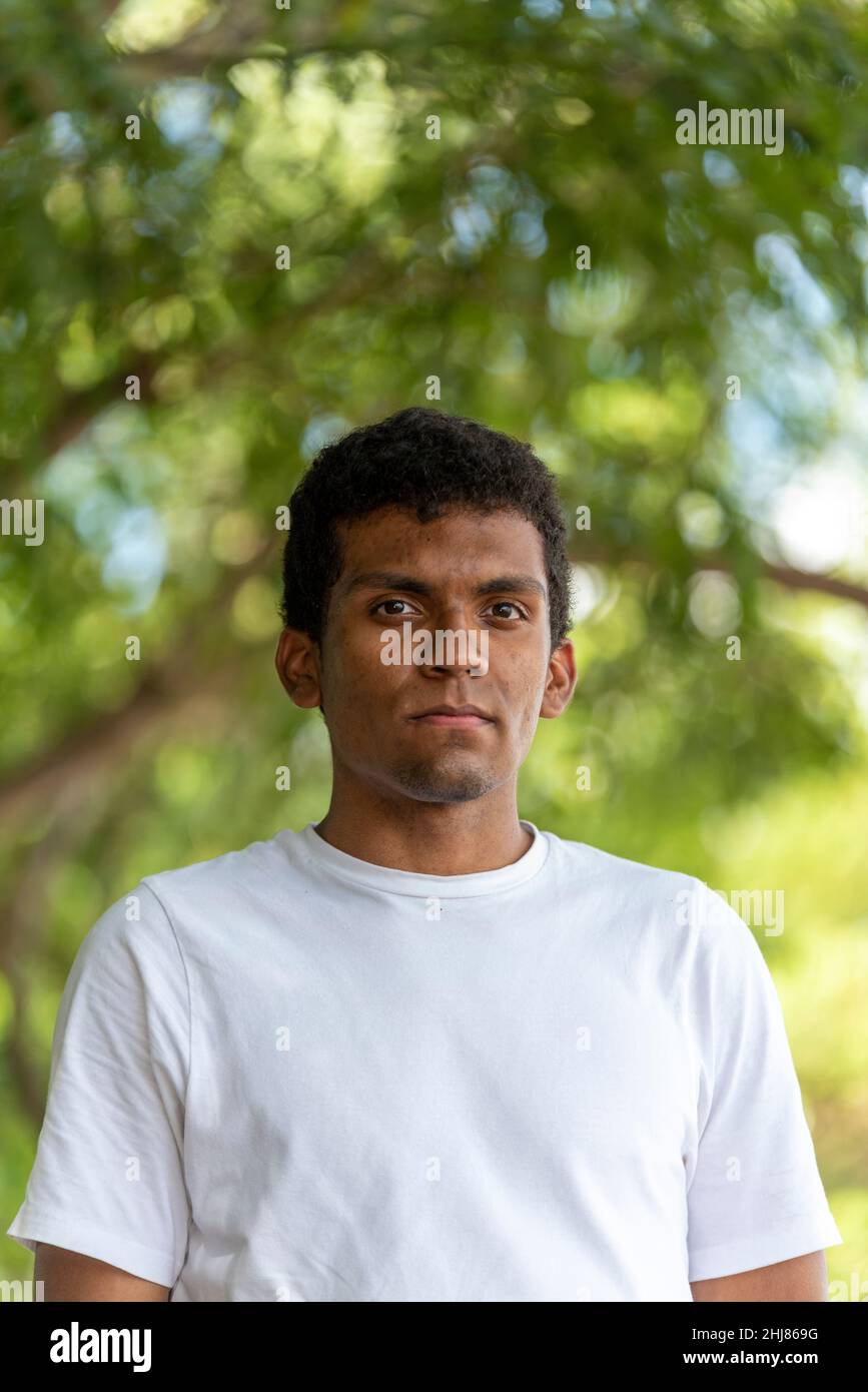 Ritratto di giovane latino sicuro indossando una t-shirt in un parco pubblico. Foto Stock